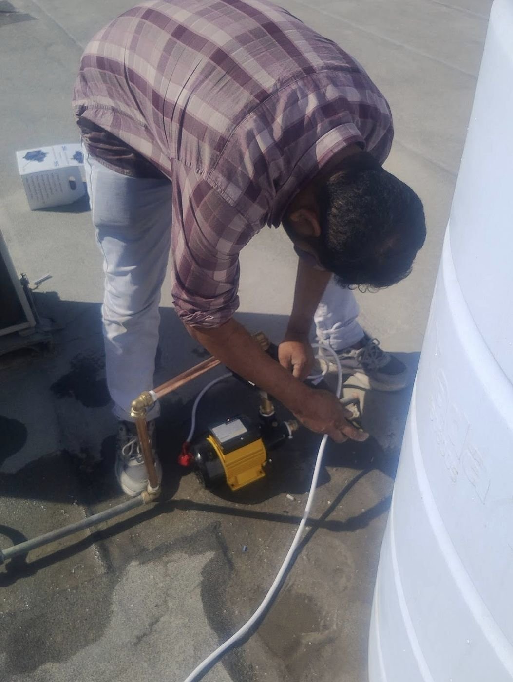 Technician installing a water pump on a rooftop