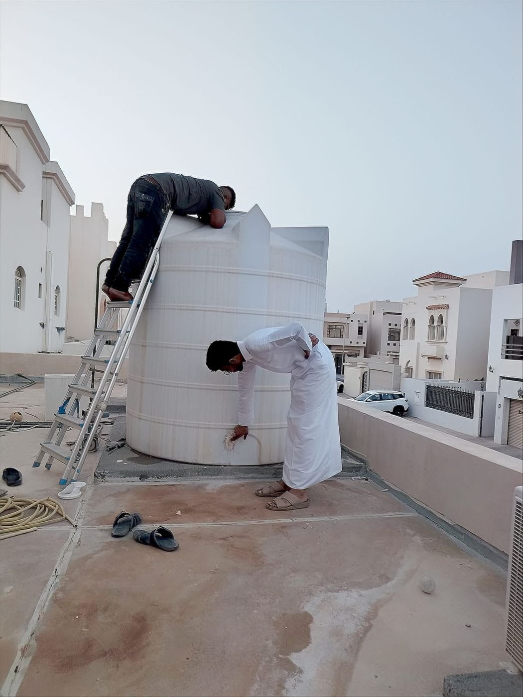Two technicians servicing a rooftop water tank