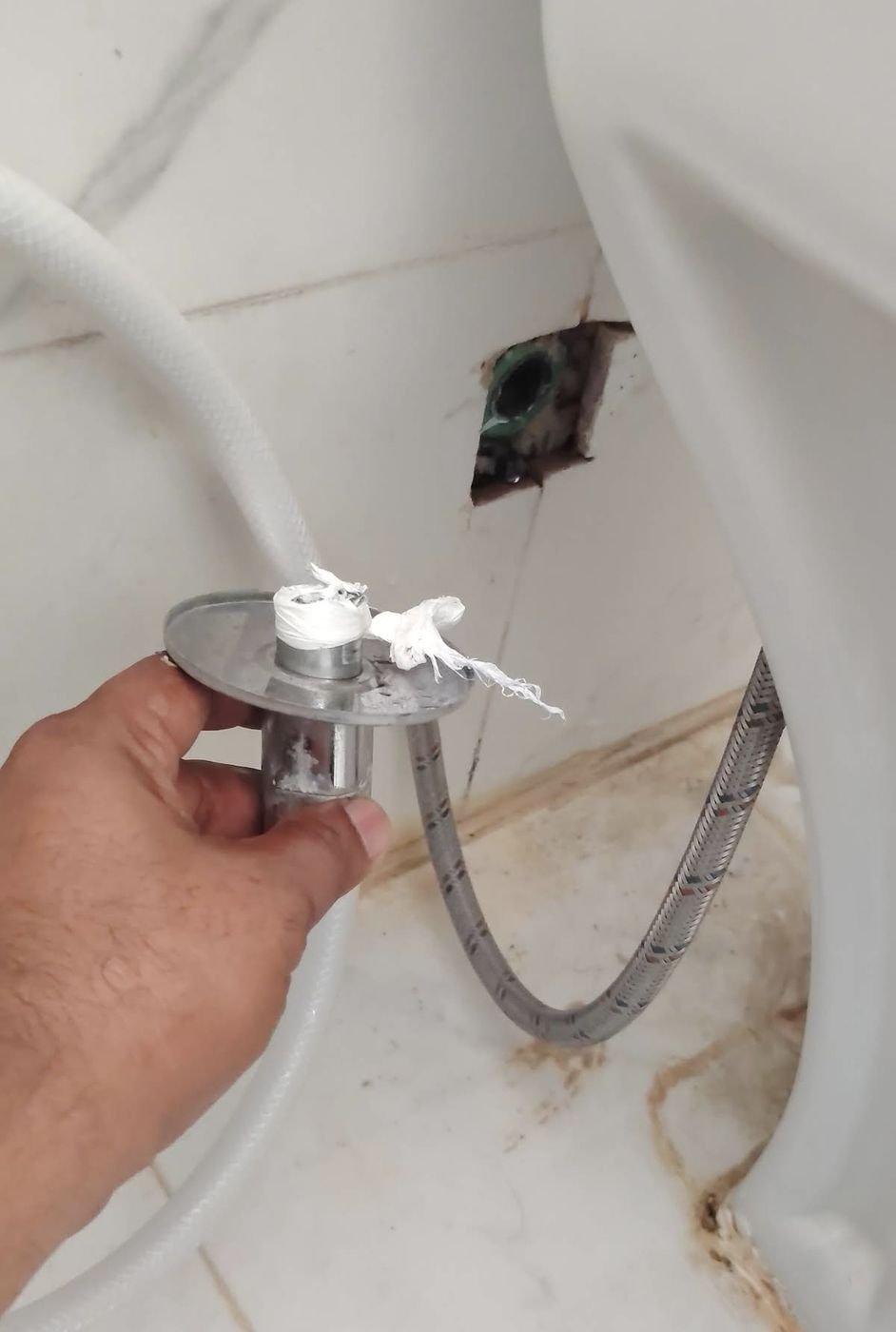 Hand fitting a chrome valve to wall pipework